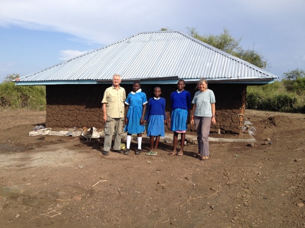 Three daughters with Chair and Vice-Chair of Watu Kwa Watu in front of partially rebuild house.